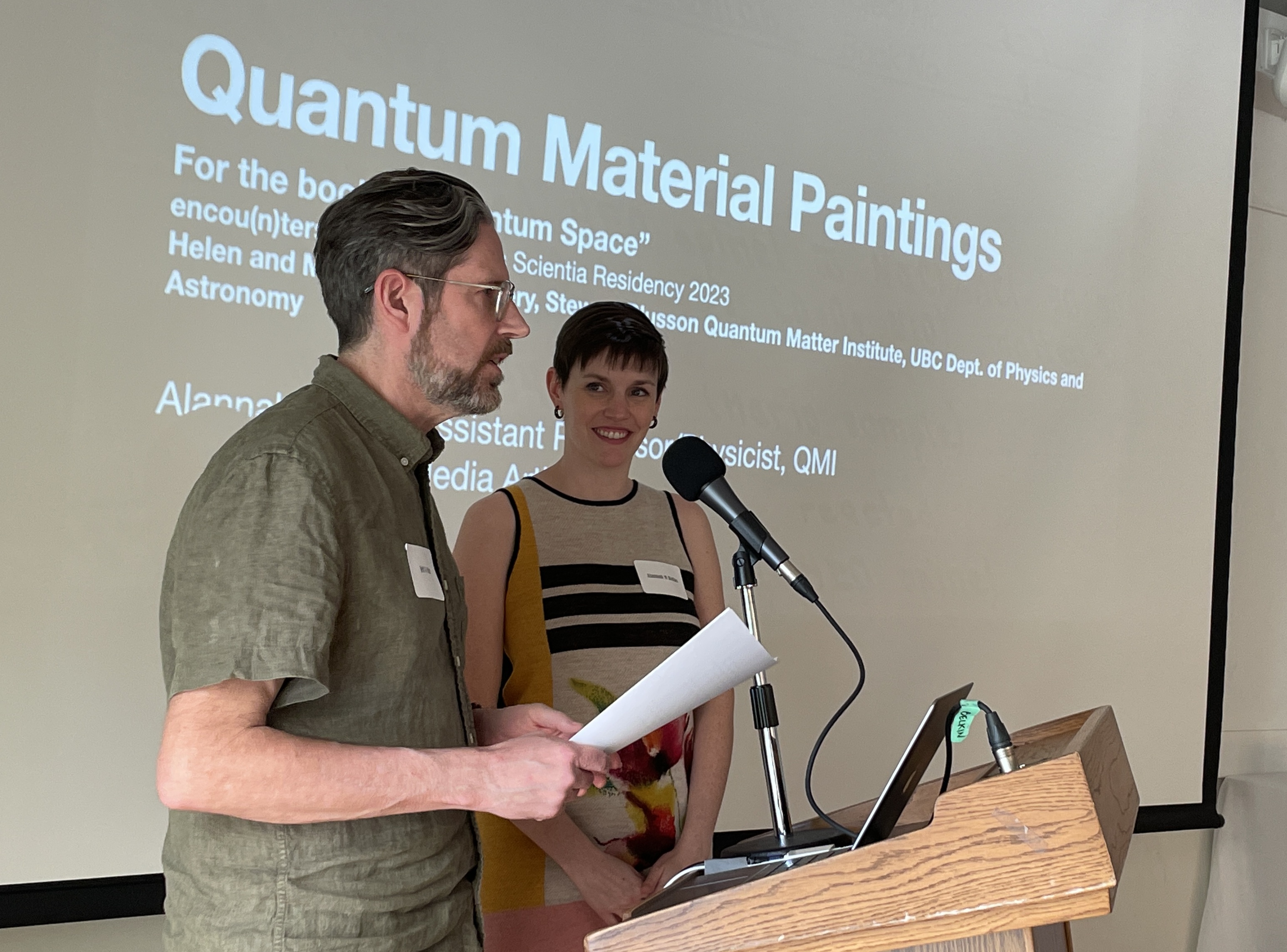 Artist and scientist give a collaborative talk behind a podium